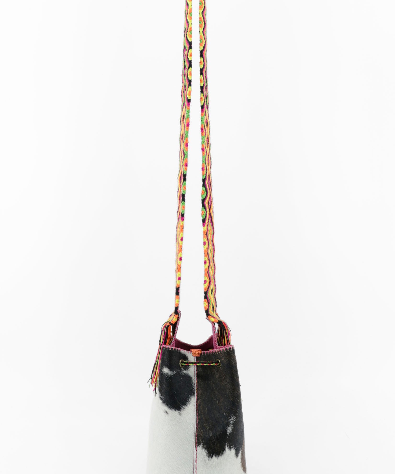Detalle de la parte trasera del bolso de estampado de vaca y cuero fucsia con correa Wayuu de colores vibrantes.